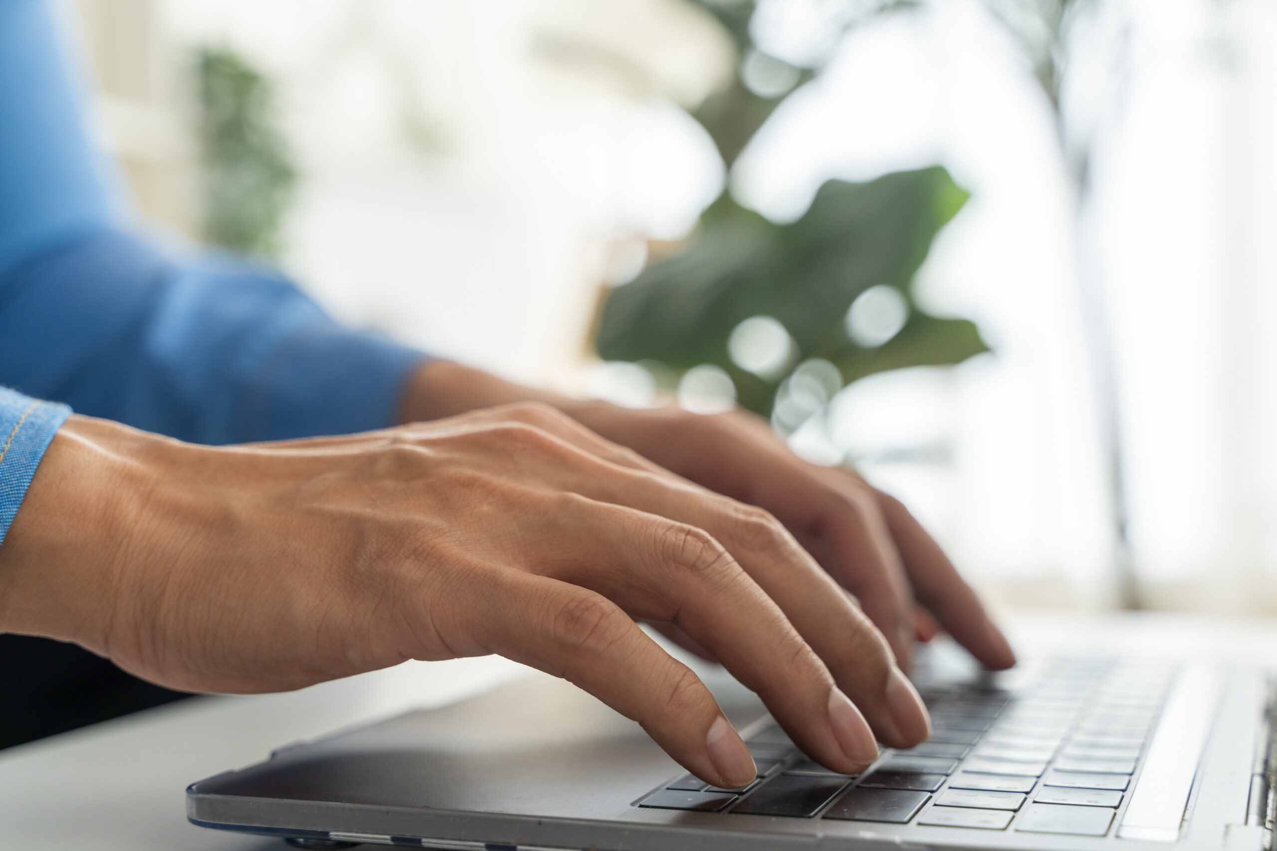 Close-up of hands typing on a laptop keyboard while configuring a business system