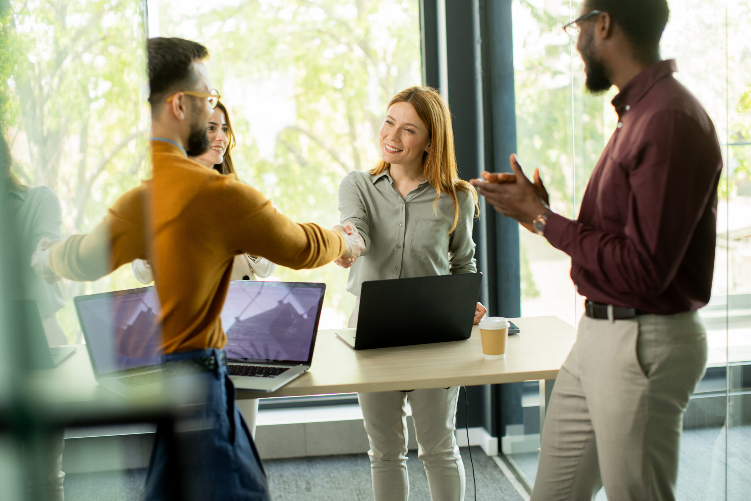 Two professionals shaking hands in a bright, open office
