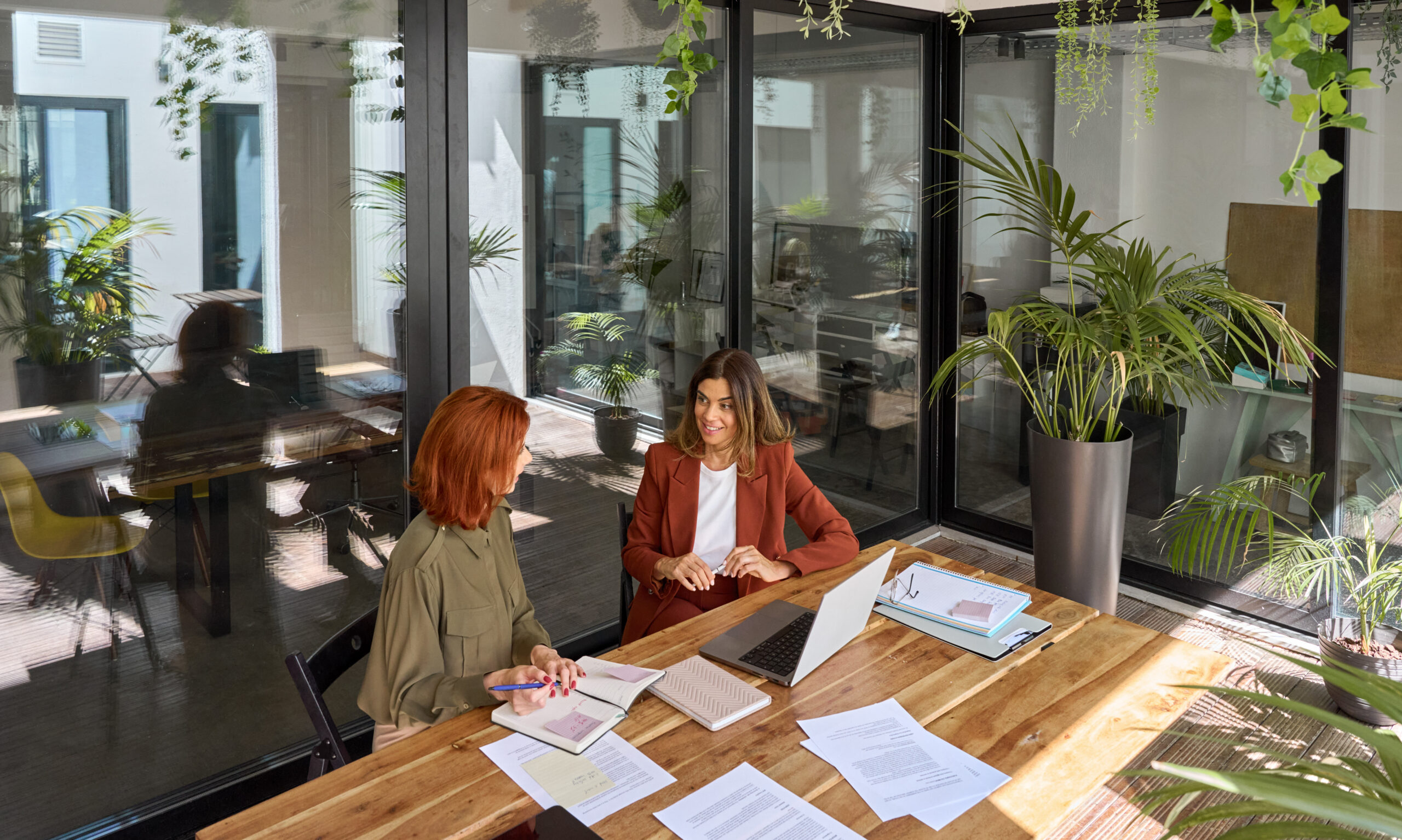 Two professionals in conversation at a desk in a bright office