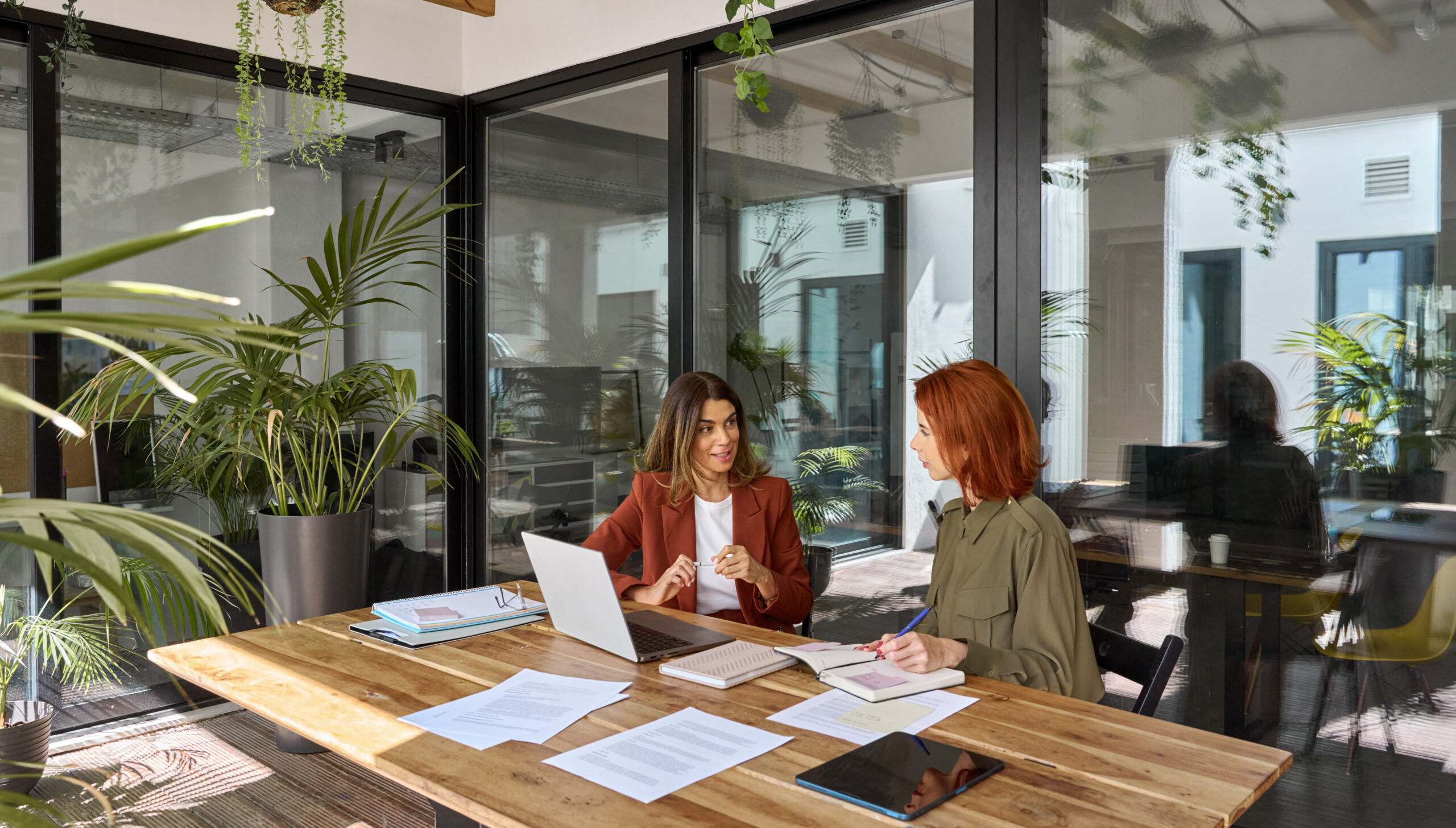 Two colleagues reviewing work together at a desk in a bright office